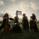 Mawiza performing acoustically in a field with a Mapuche flag